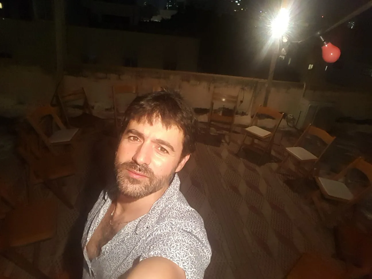 גדעון איגרא על הגג בלילה, מאחוריו הכיסאות הריקים של המעגל